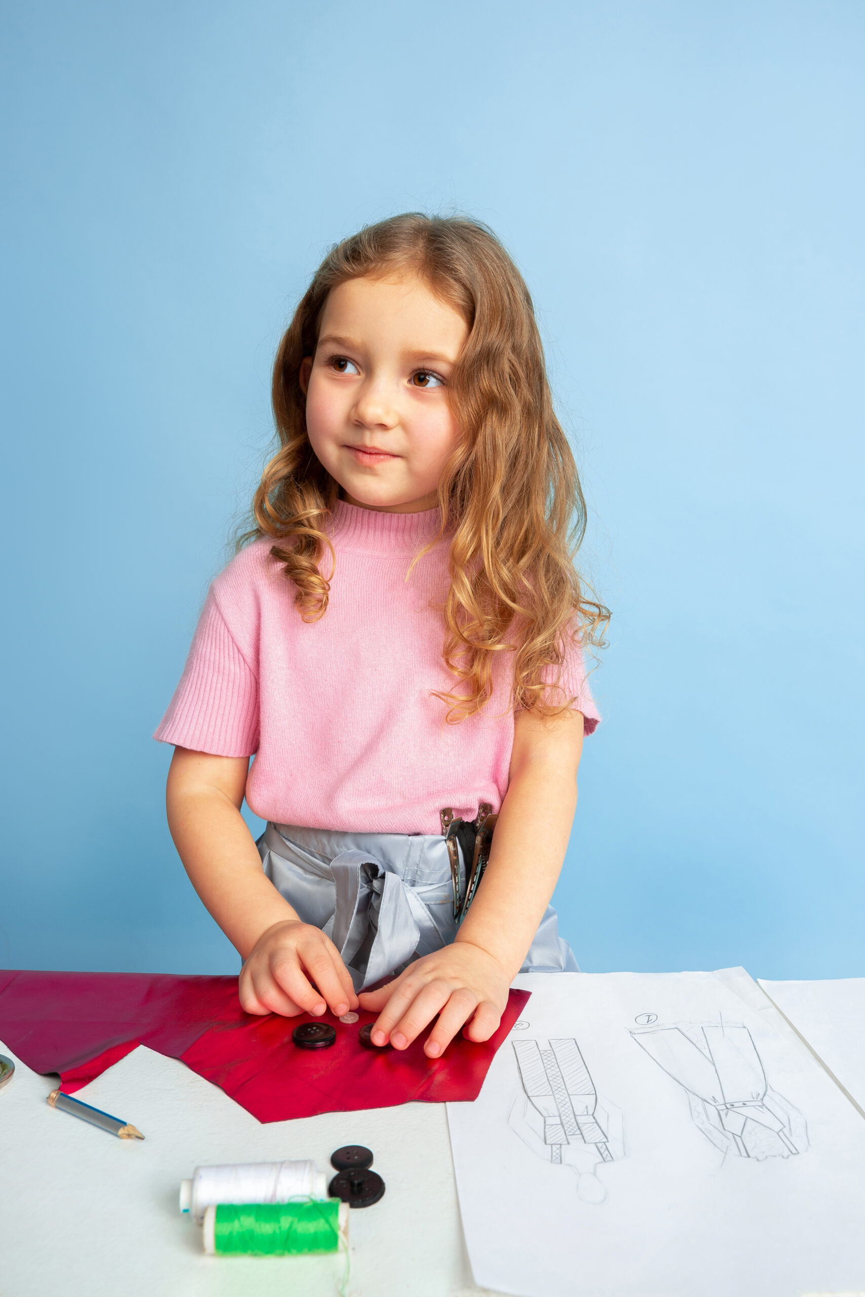 Little girl dreaming about future profession of seamstress